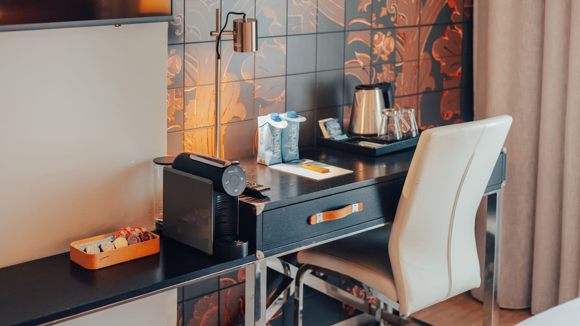 Hotel room desk featuring Nespresso machine, electric kettle, and patterned wall.