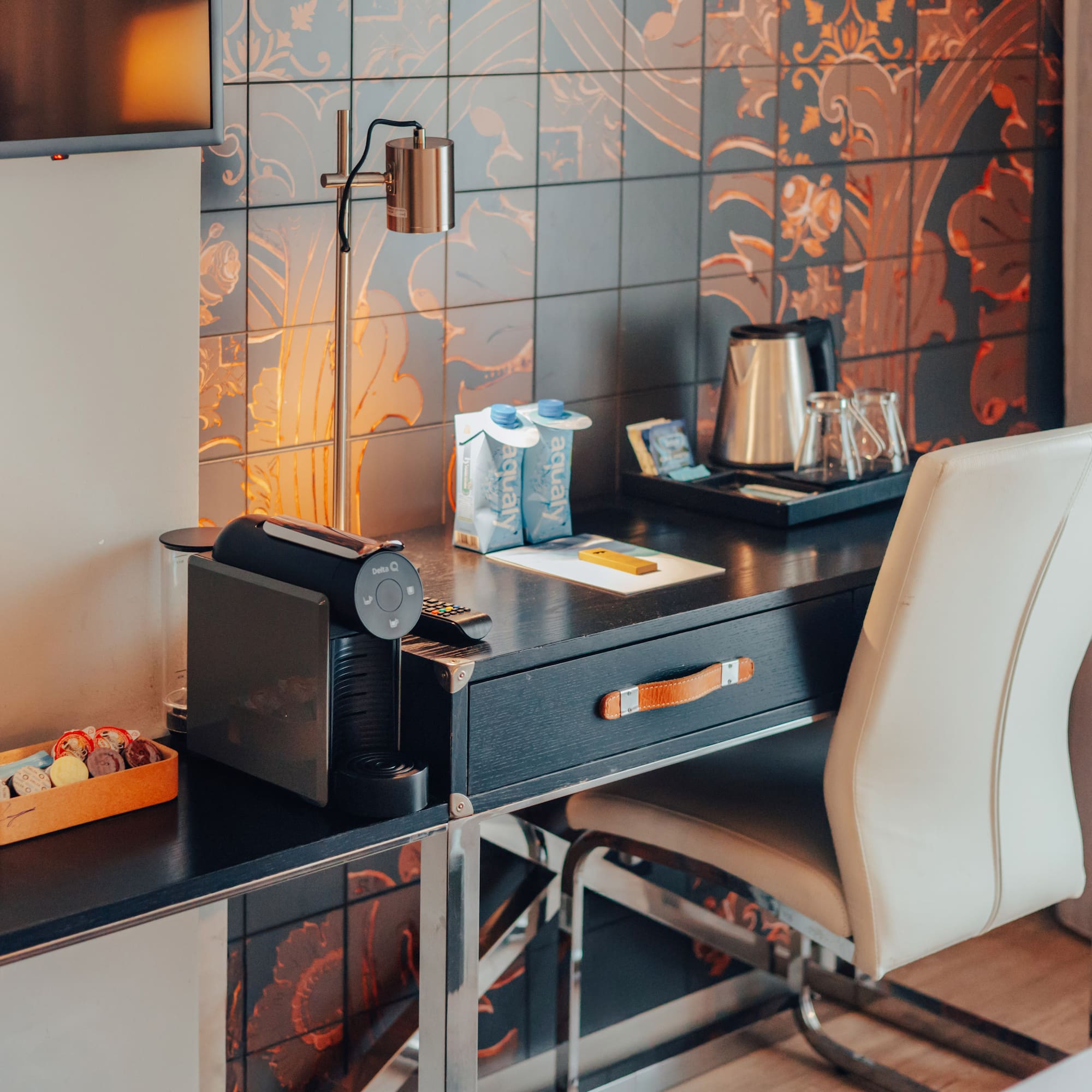 Hotel room desk featuring Nespresso machine, electric kettle, and patterned wall.
