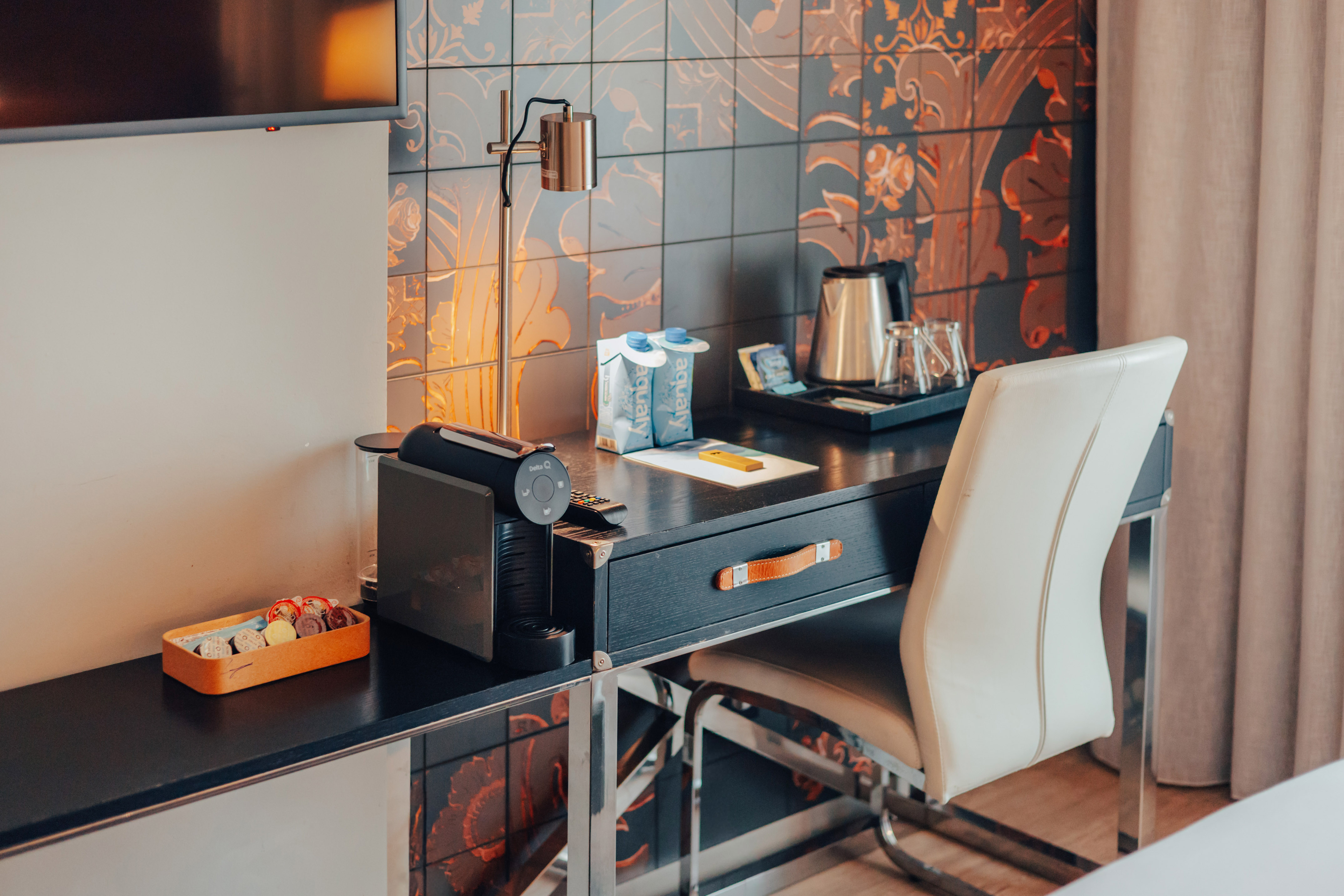 Hotel room desk featuring Nespresso machine, electric kettle, and patterned wall.