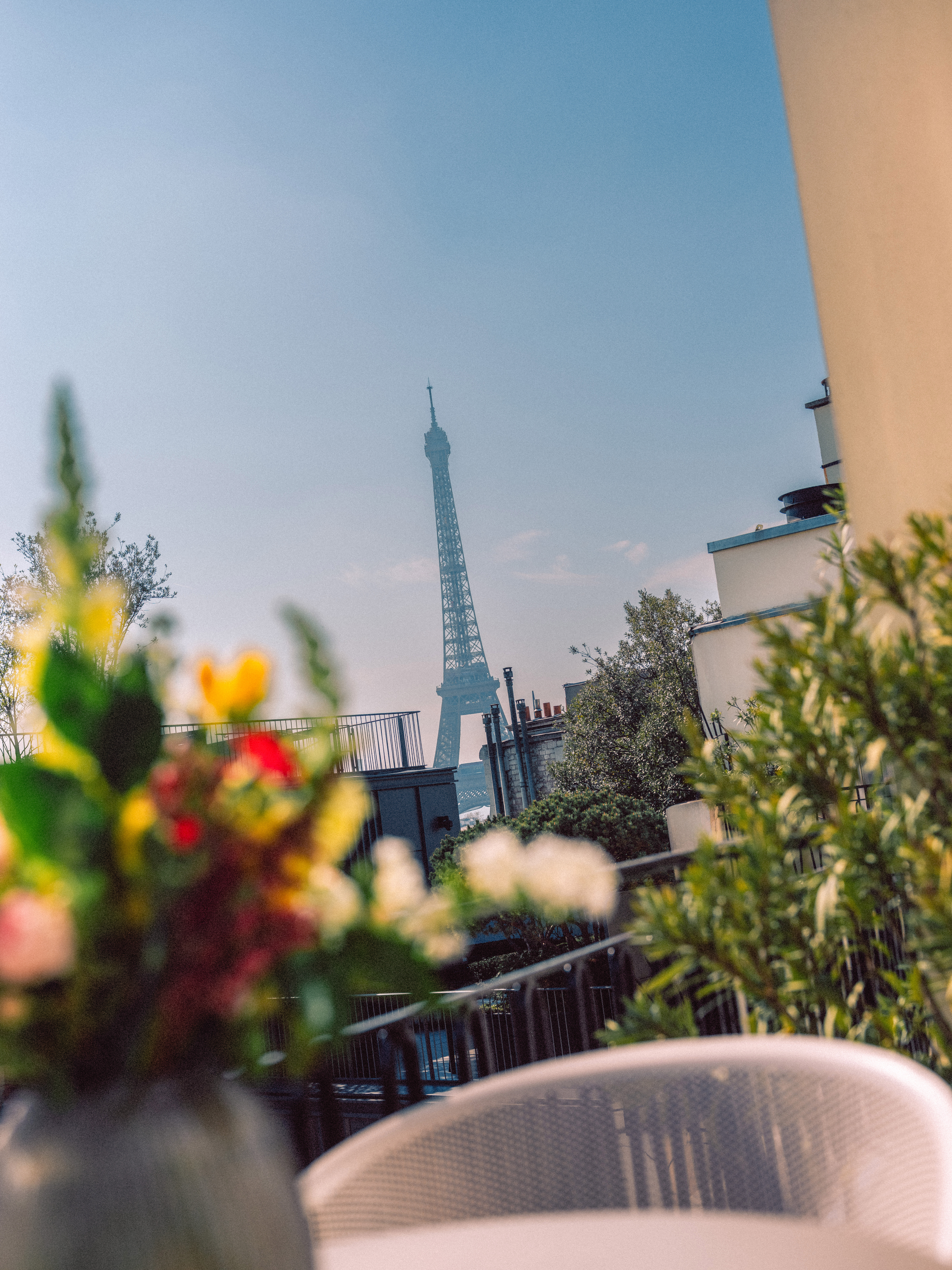 Eiffel Tower view from a Parisian balcony with blurred colorful flowers.