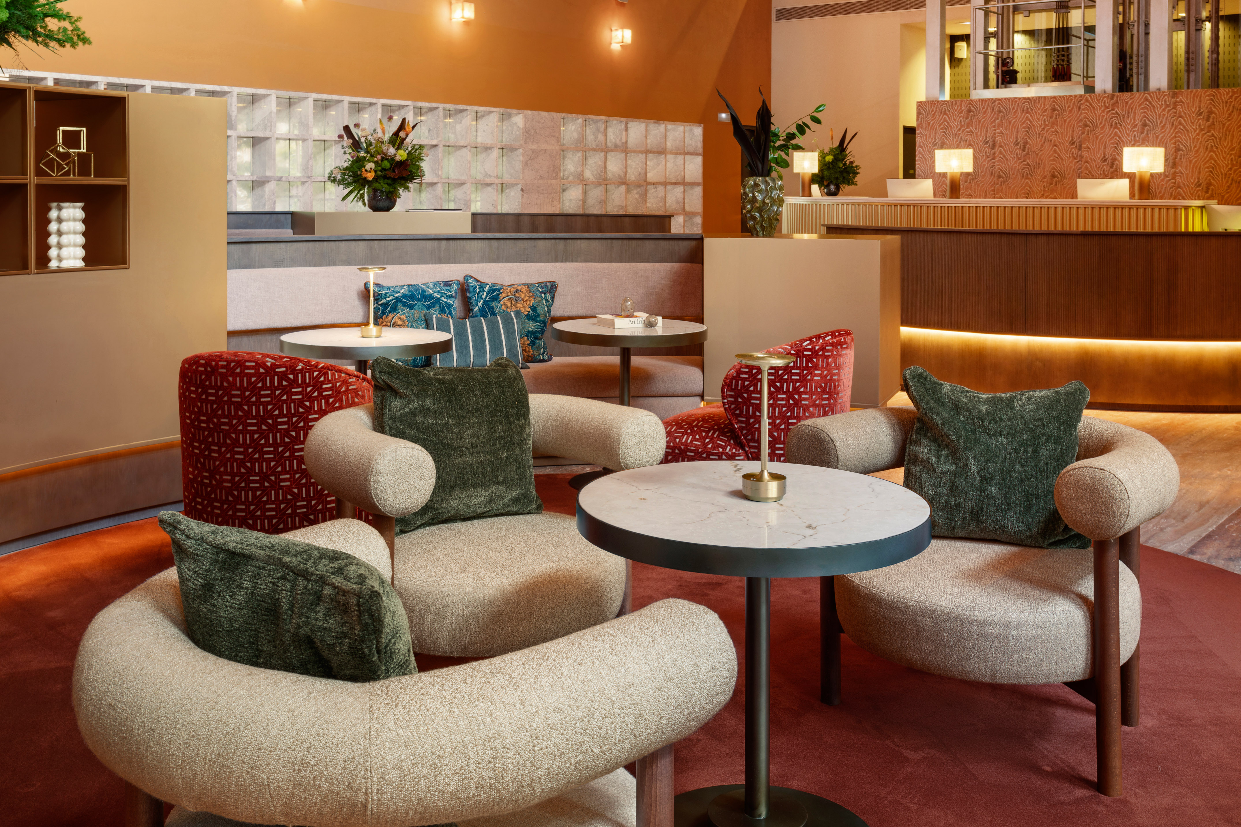 Hotel lobby lounge with modern seating, round tables, and reception desk.