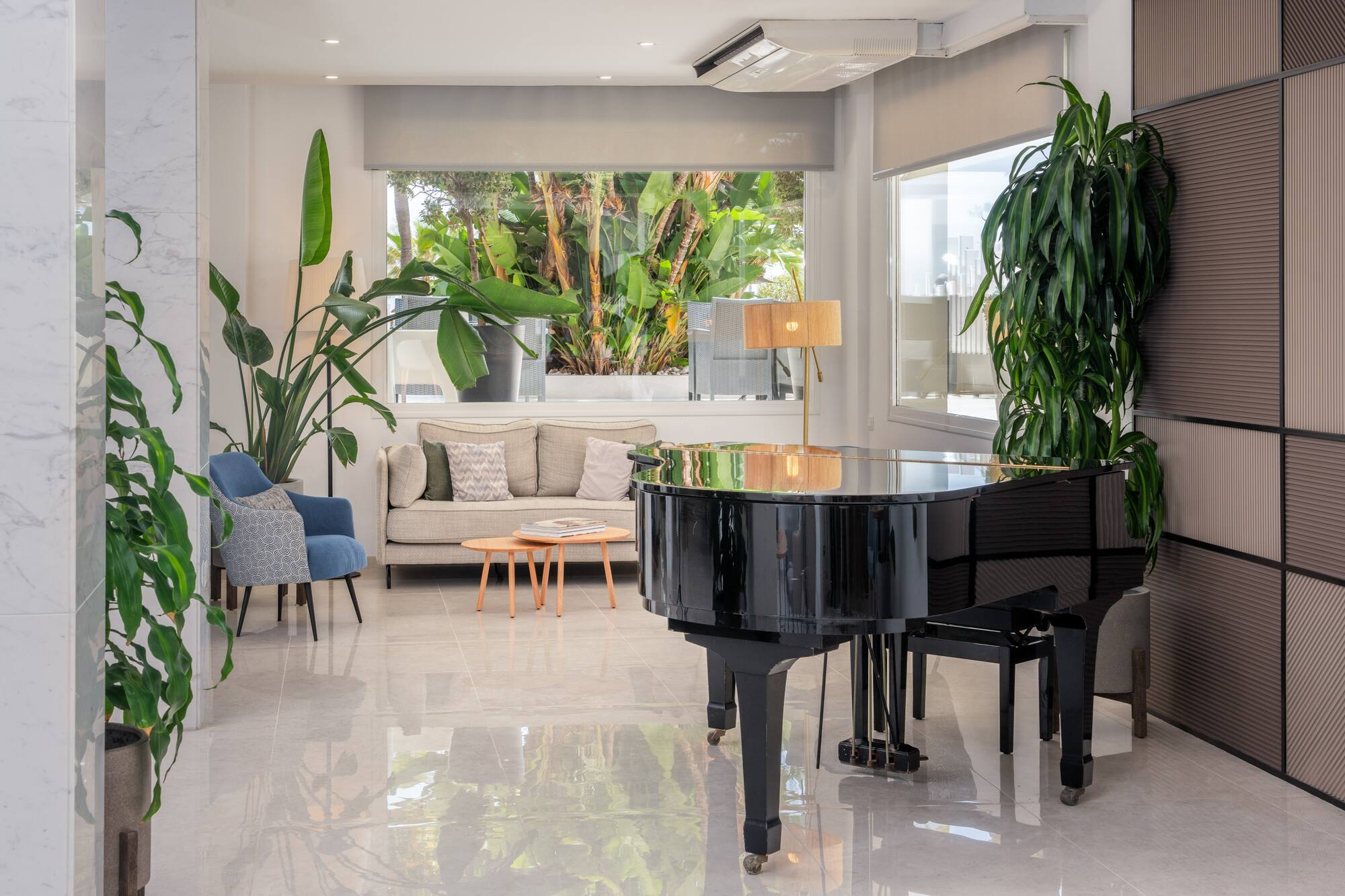 Elegant modern lounge with black grand piano, sofa, and lush tropical view.