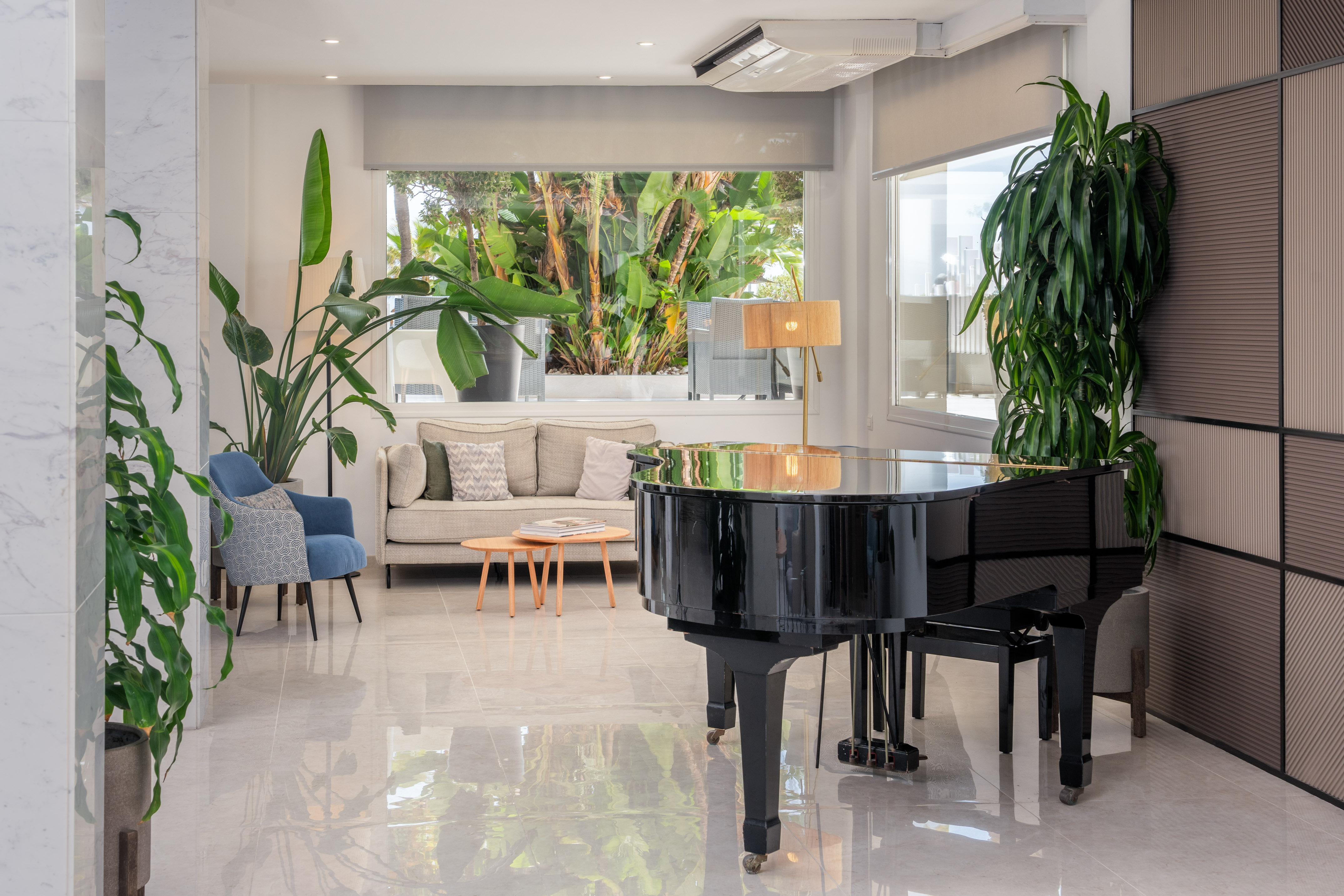 Elegant modern lounge with black grand piano, sofa, and lush tropical view.
