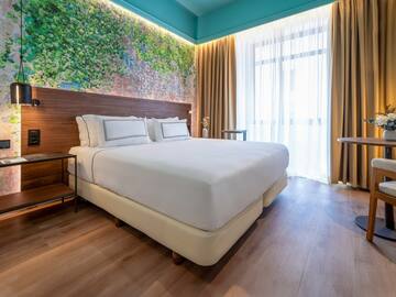 a bed with white sheets and a wood headboard in a room with a window