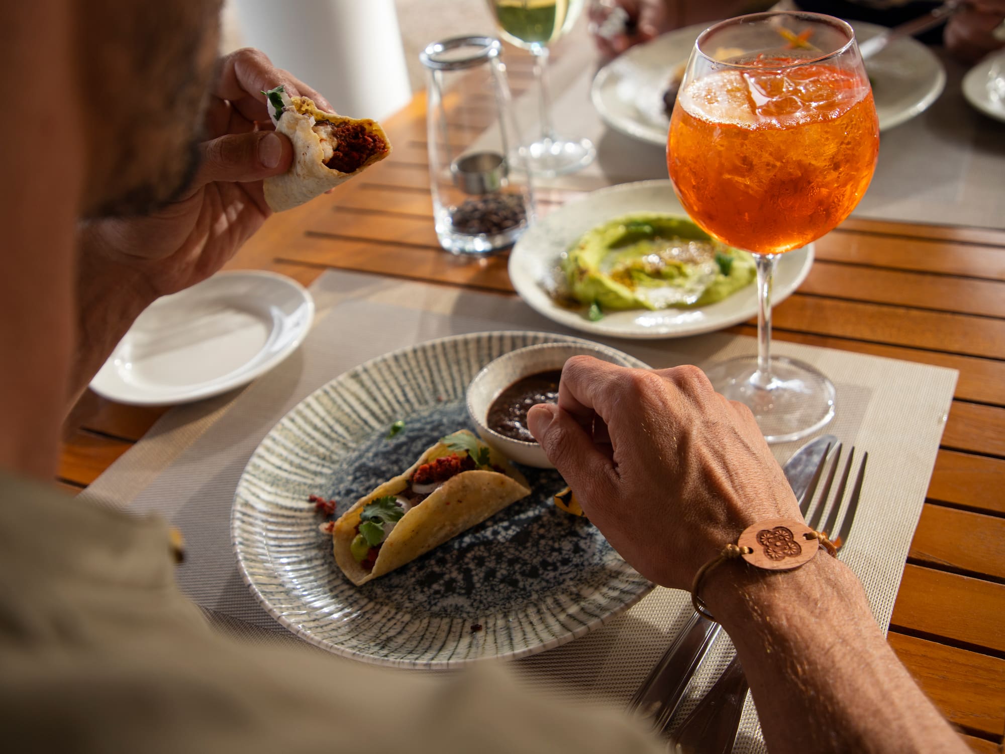 a person eating tacos on a plate with a drink