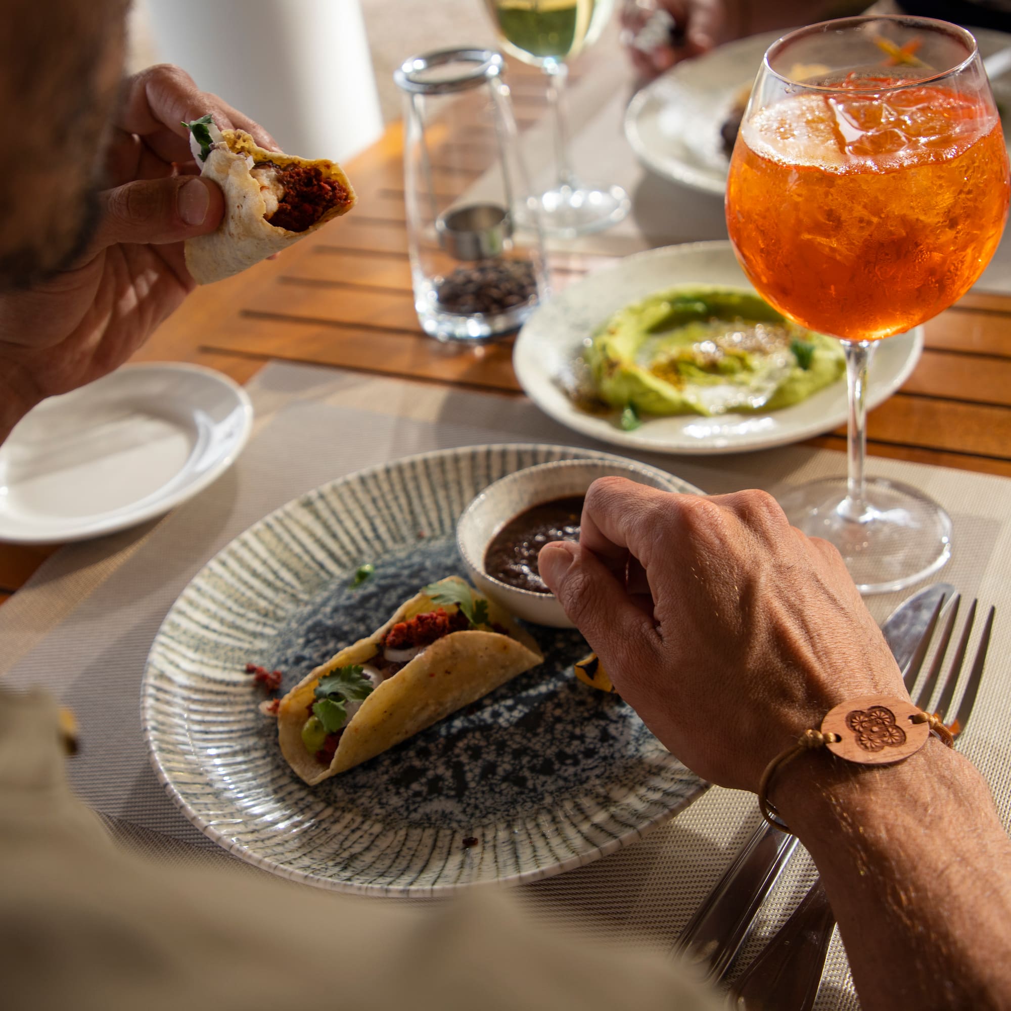a person eating tacos on a plate with a drink