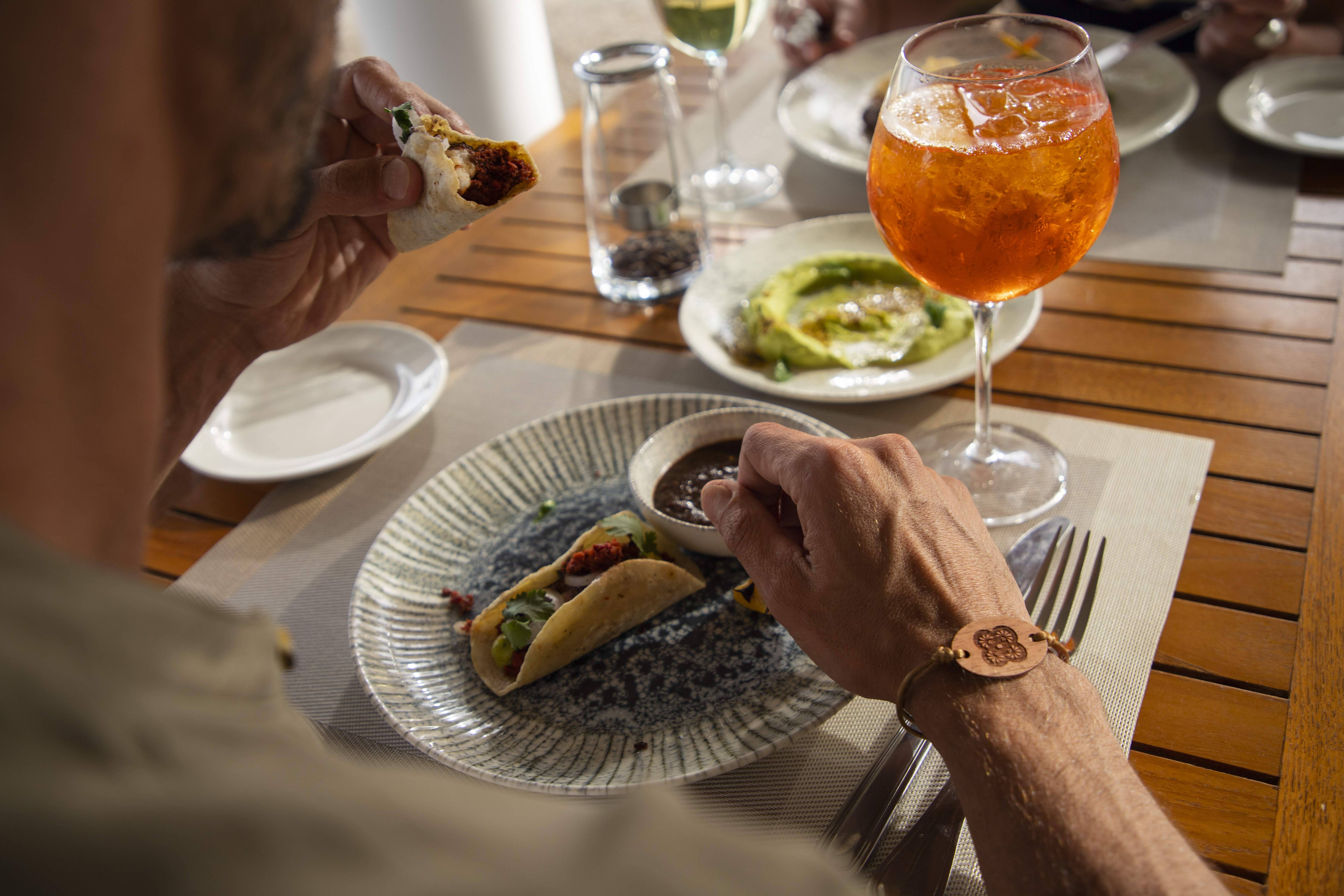 a person eating tacos on a plate with a drink