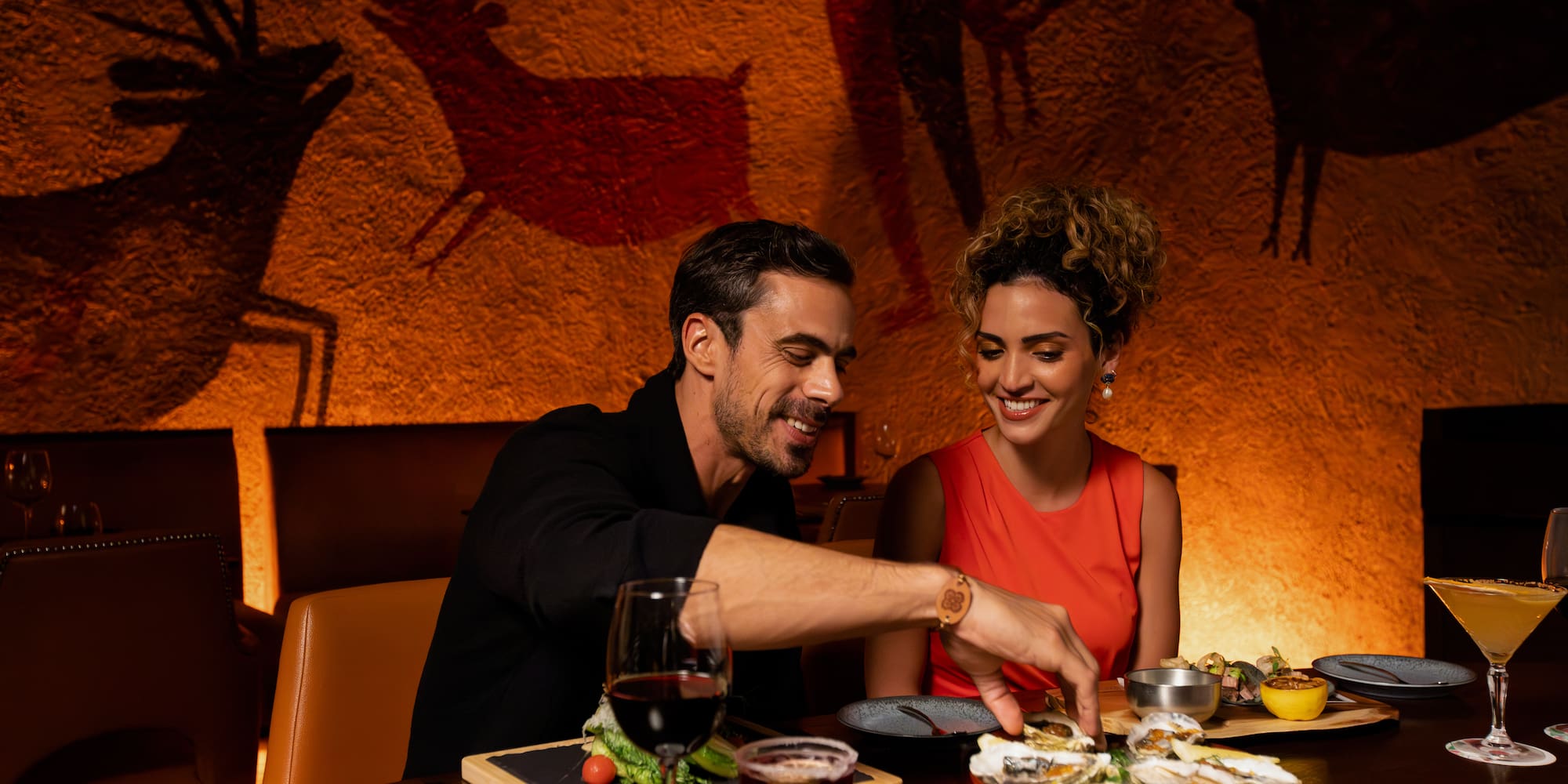 a man and woman sitting at a table with food