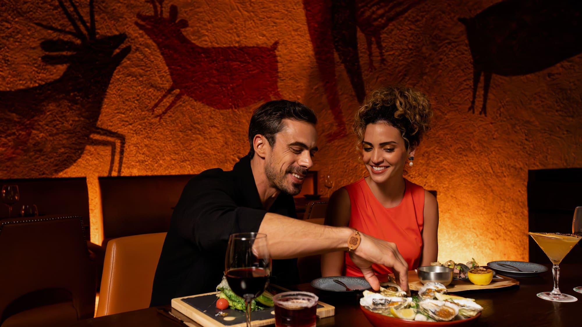 a man and woman sitting at a table with food