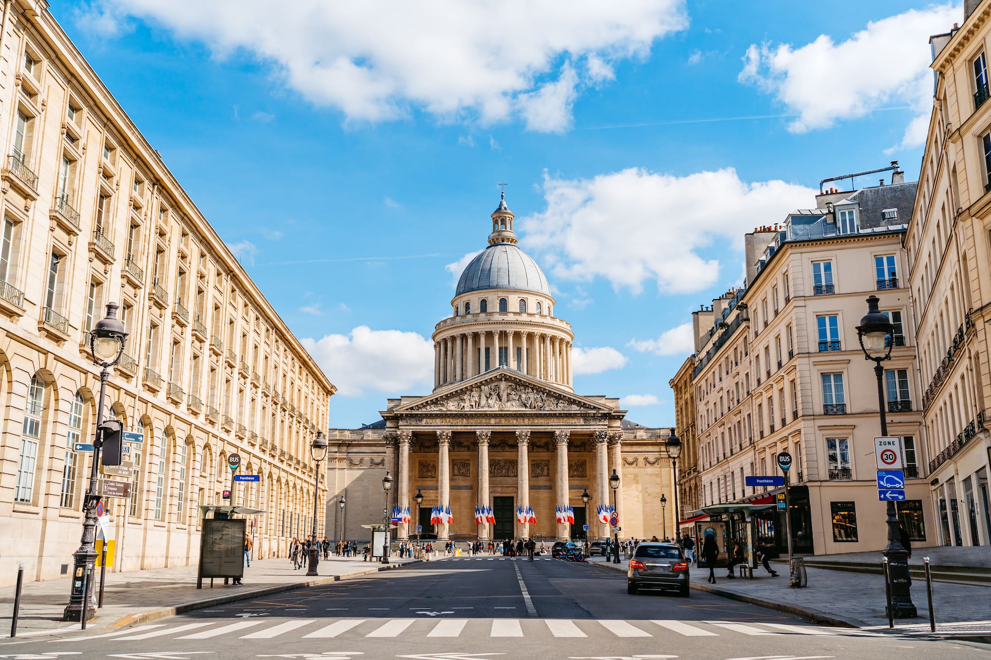a street with Panthéon and people walking around