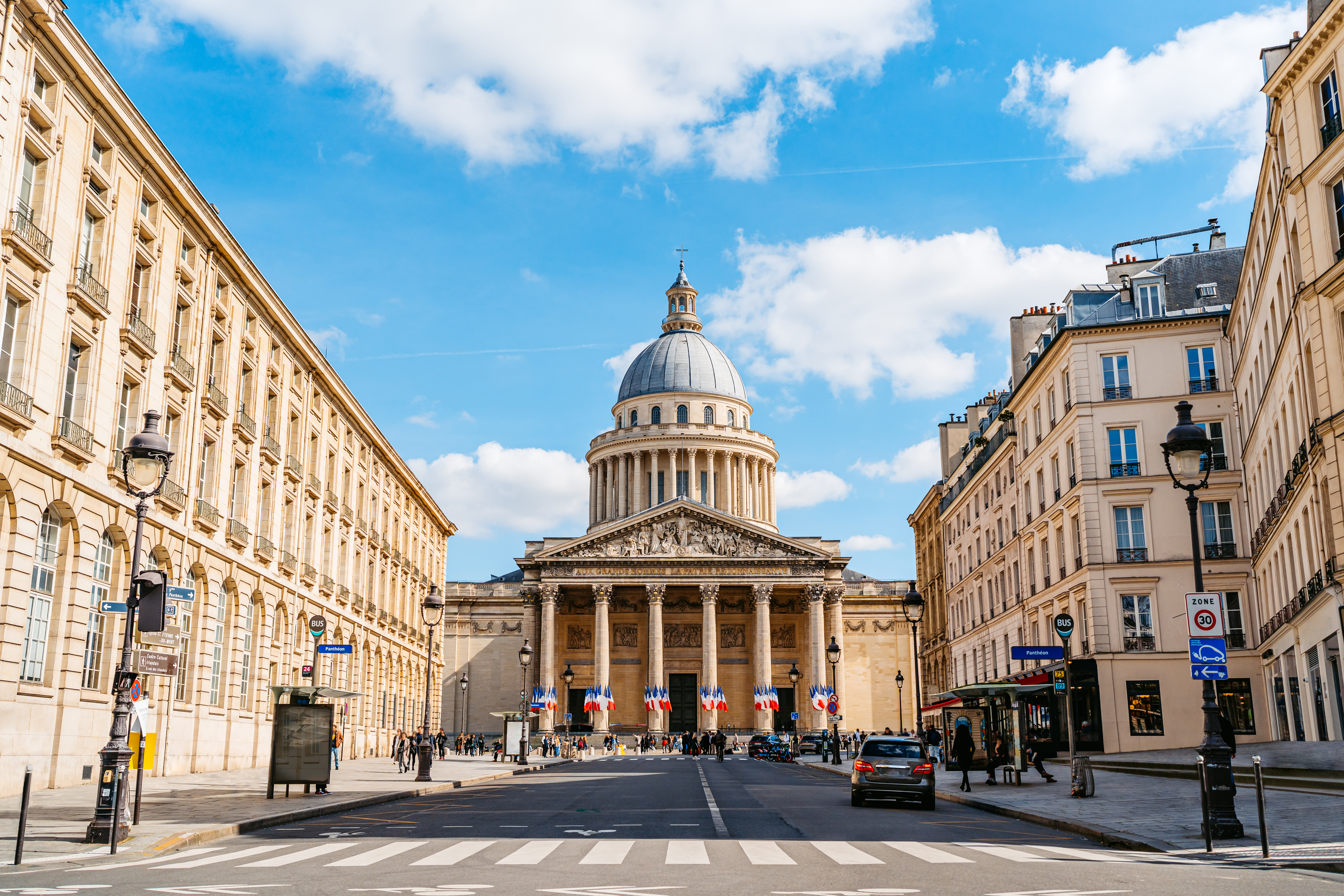 a street with Panthéon and people walking around