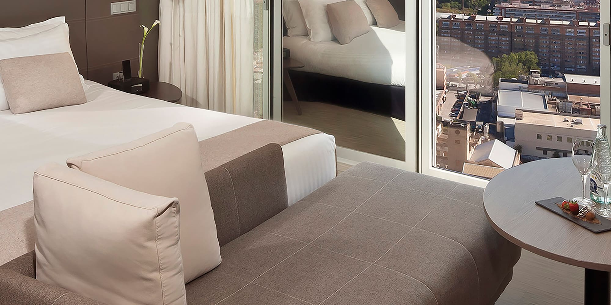 a room with a bed and a table with a view of a city