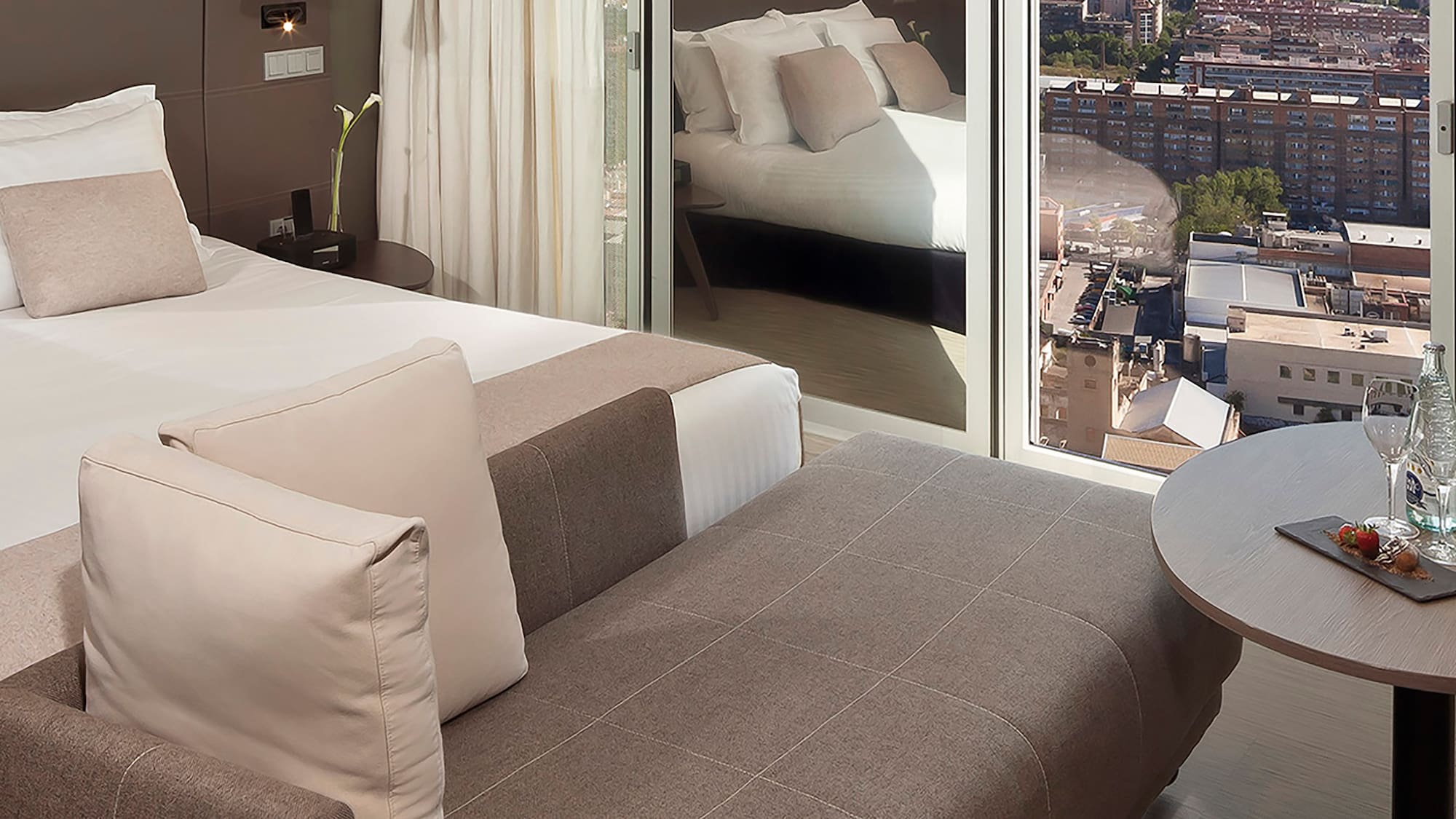 a room with a bed and a table with a view of a city