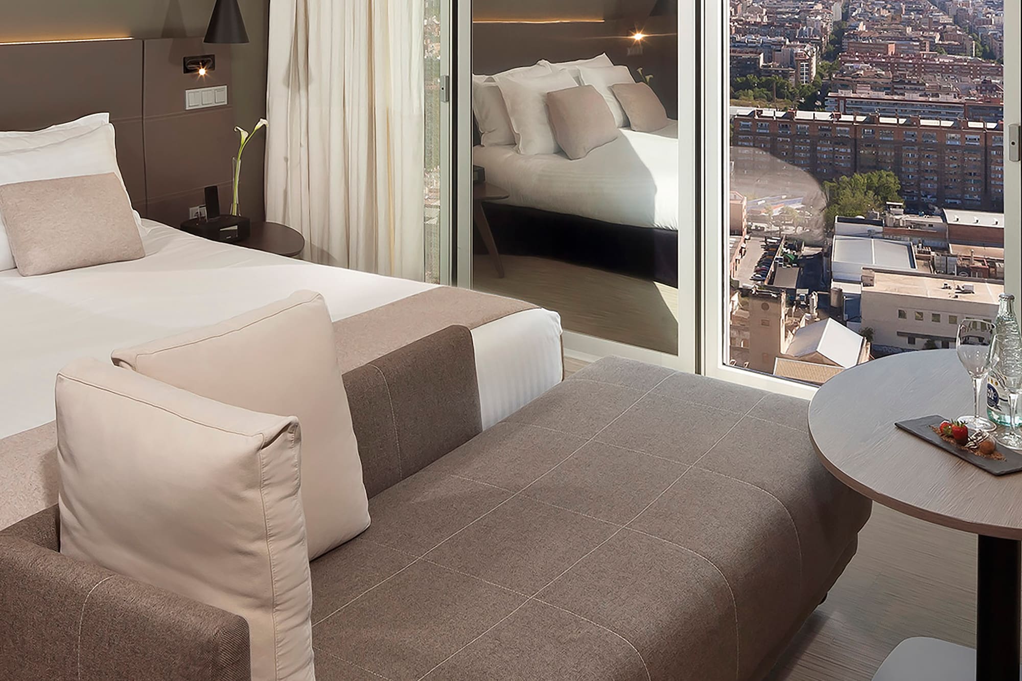 a room with a bed and a table with a view of a city