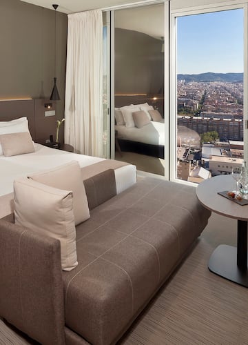a room with a bed and a table with a view of a city