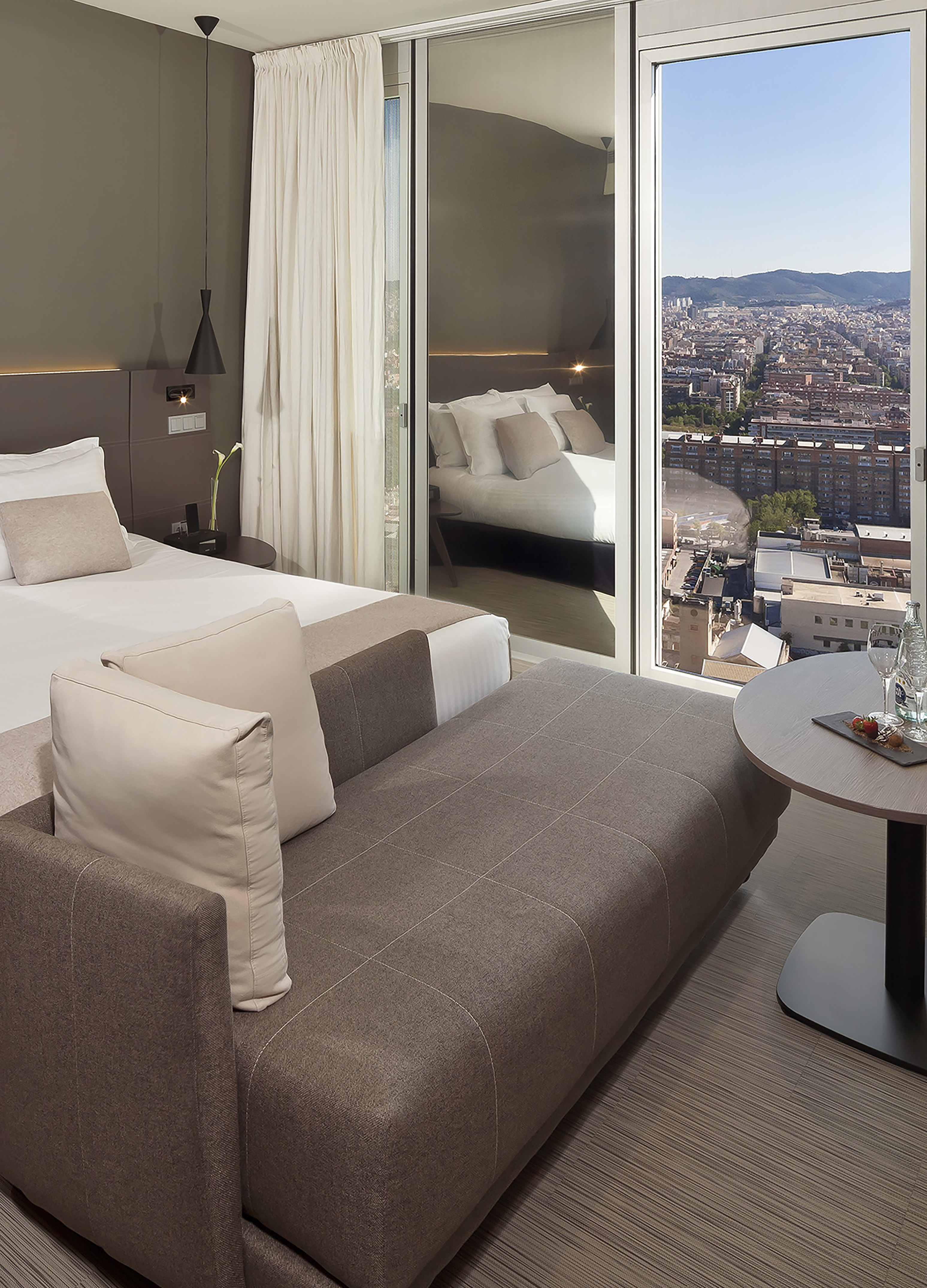 a room with a bed and a table with a view of a city