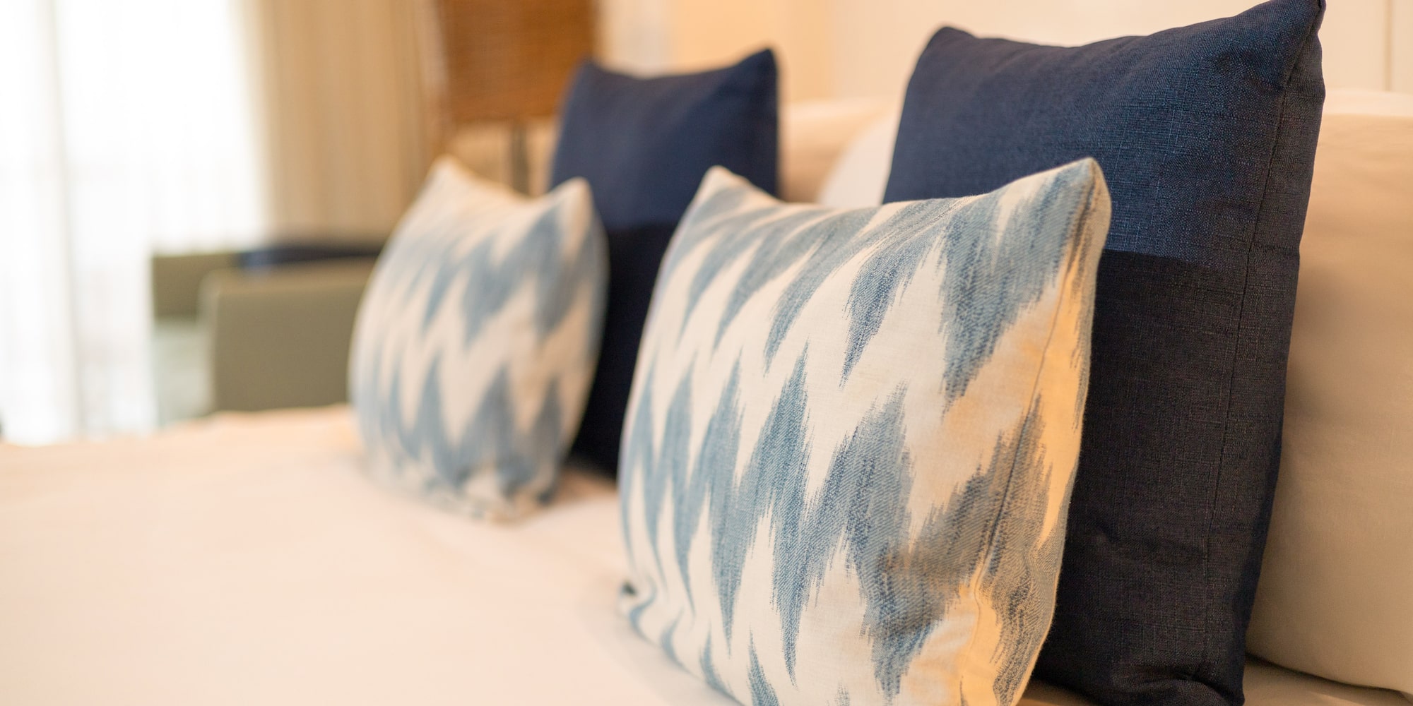 Blue and white decorative bed pillows with ikat pattern on a hotel bed.