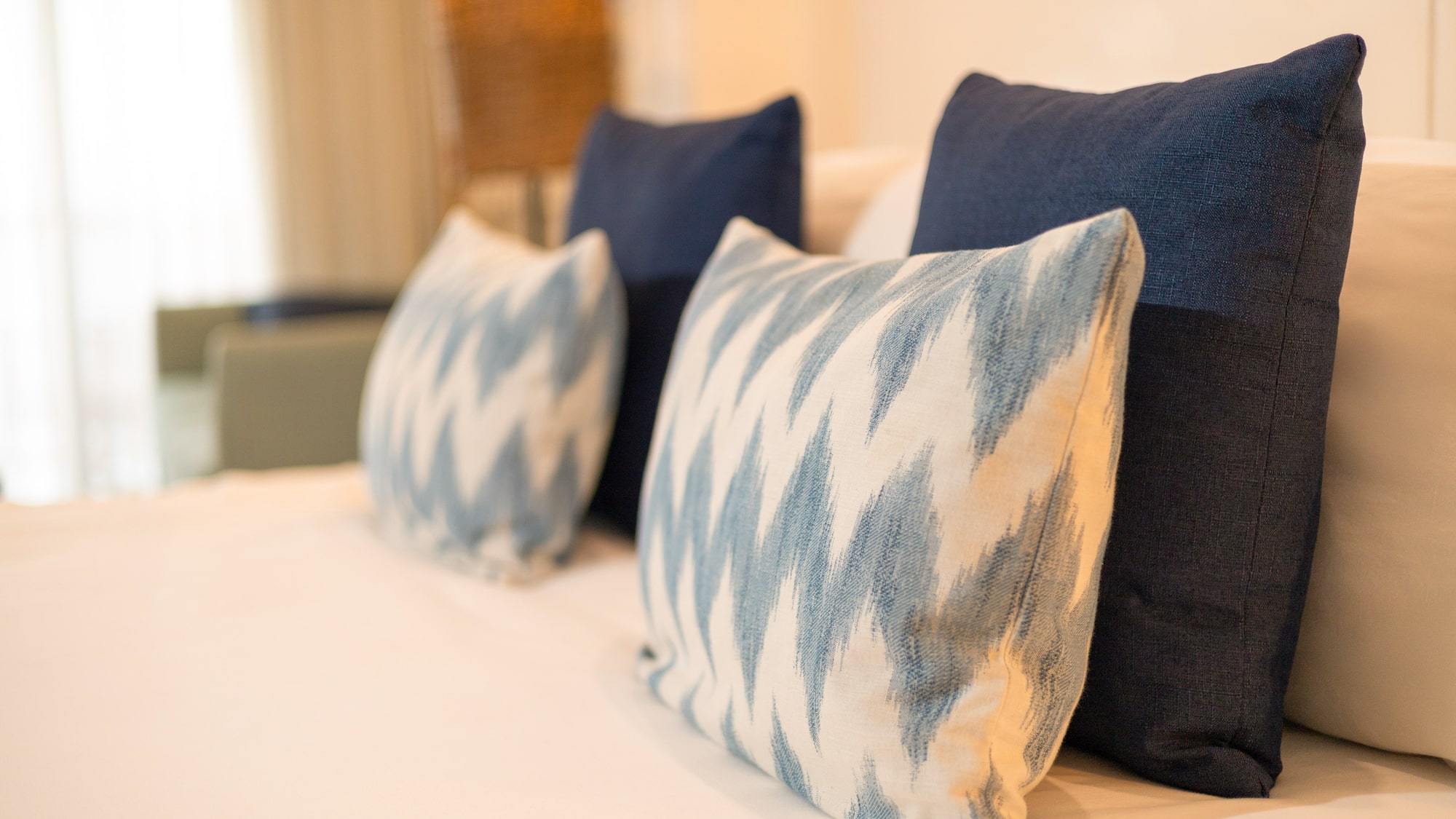 Blue and white decorative bed pillows with ikat pattern on a hotel bed.
