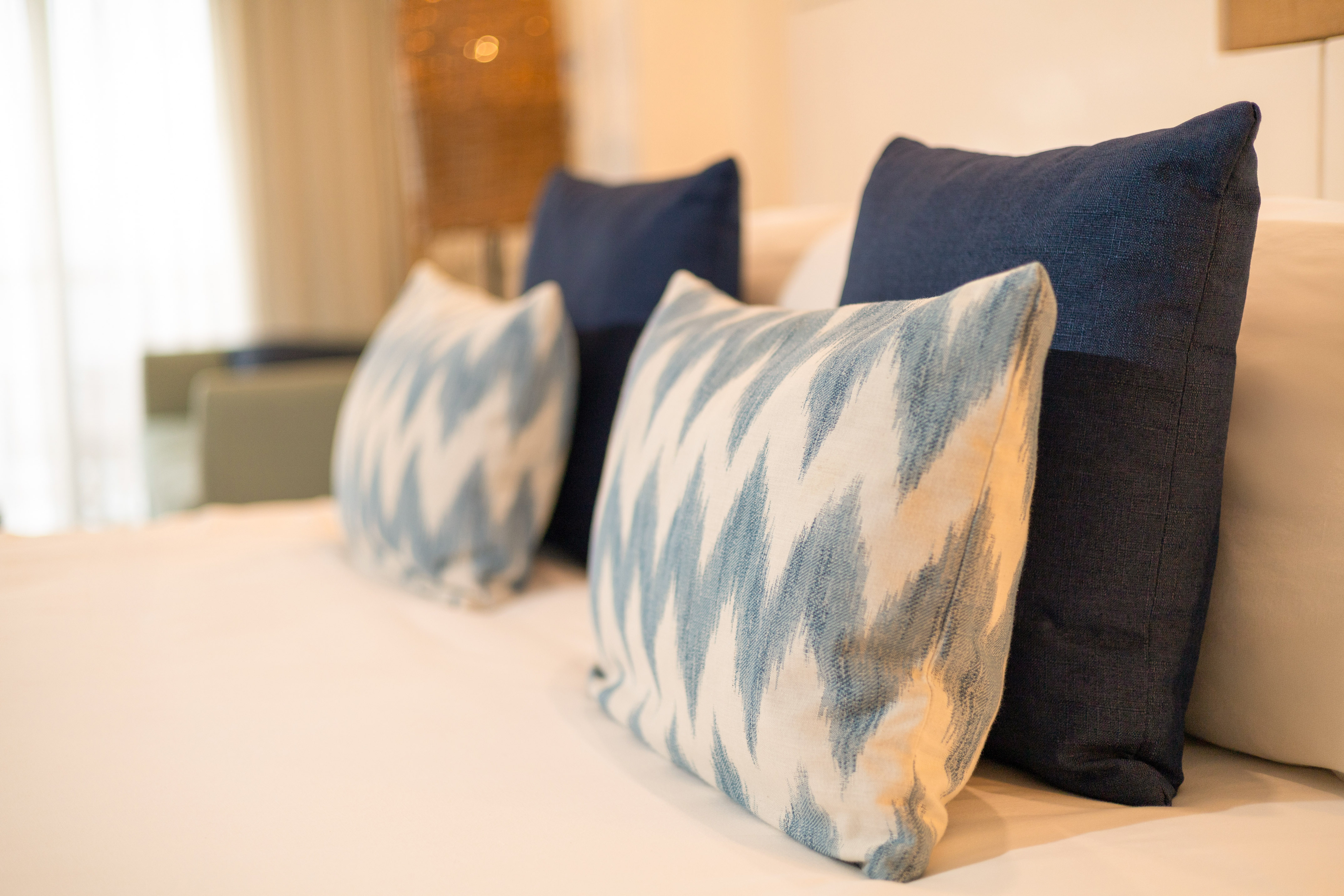 Blue and white decorative bed pillows with ikat pattern on a hotel bed.