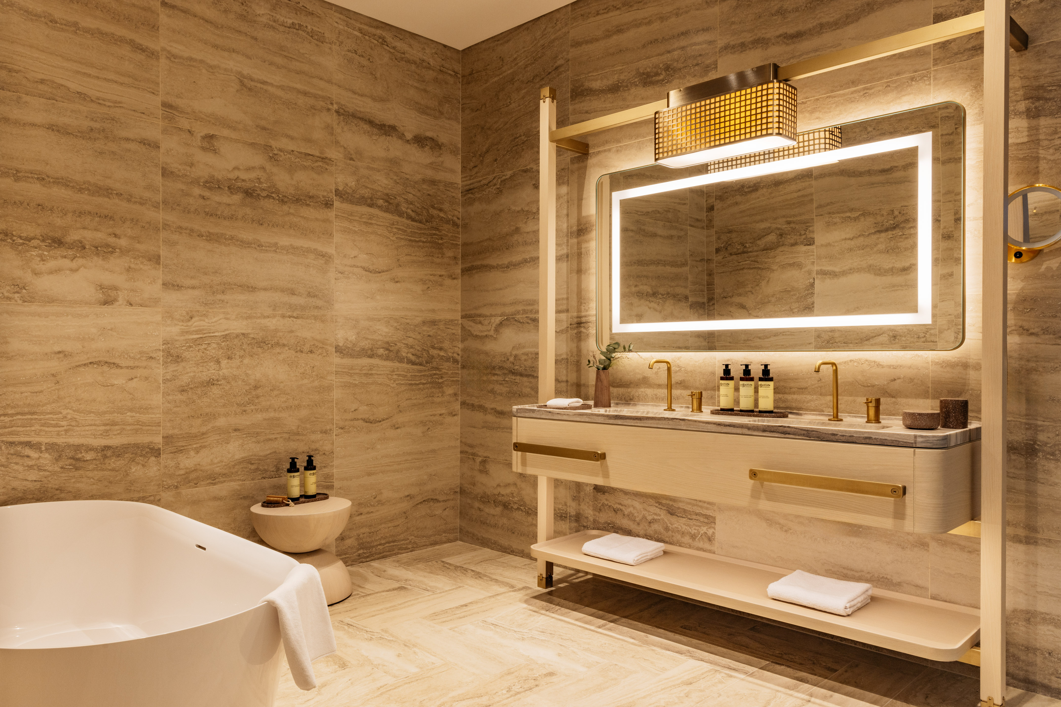 Modern luxury bathroom with natural stone, freestanding tub, and double vanity.