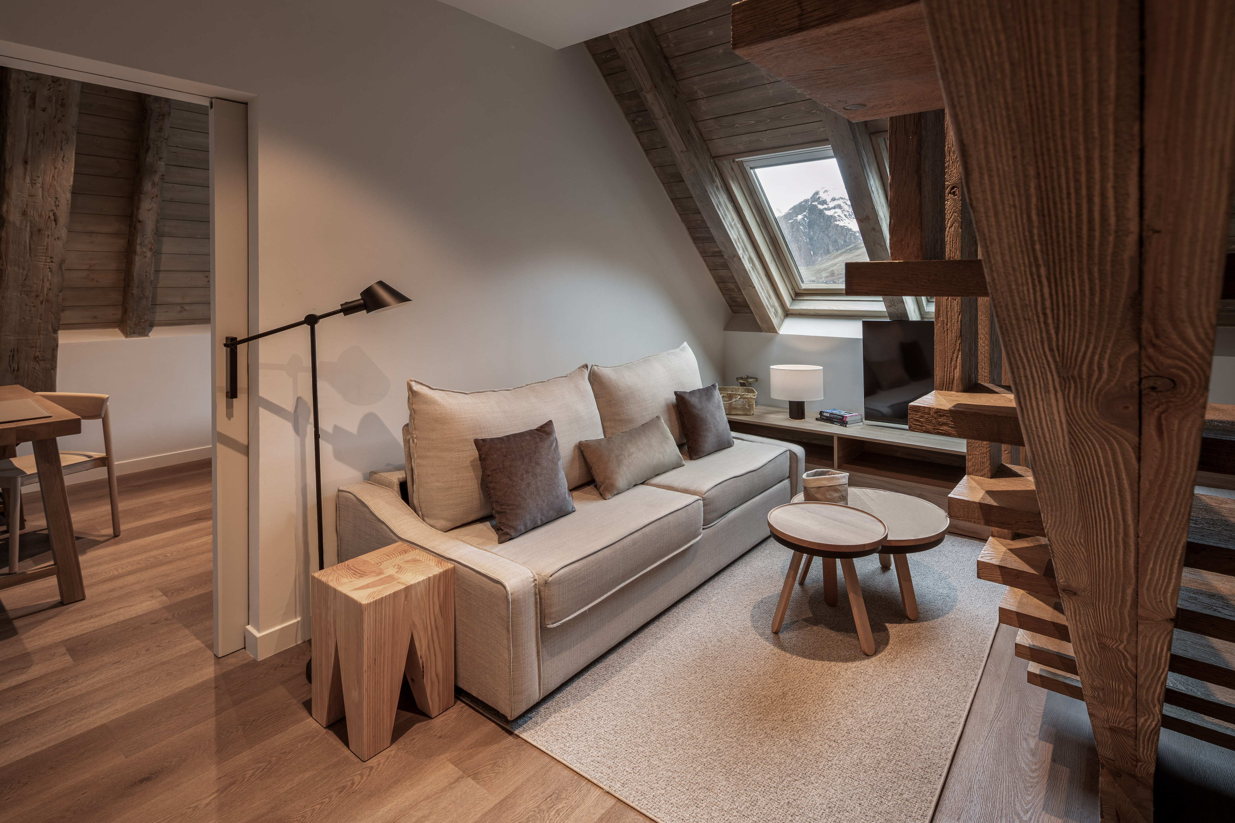 Cozy living room, sofa, wooden beams, and mountain view from attic window.