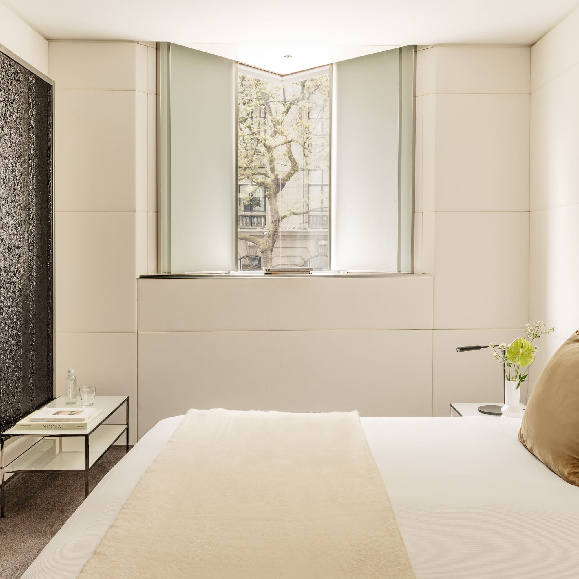 a bed with a pillow and a table with flowers