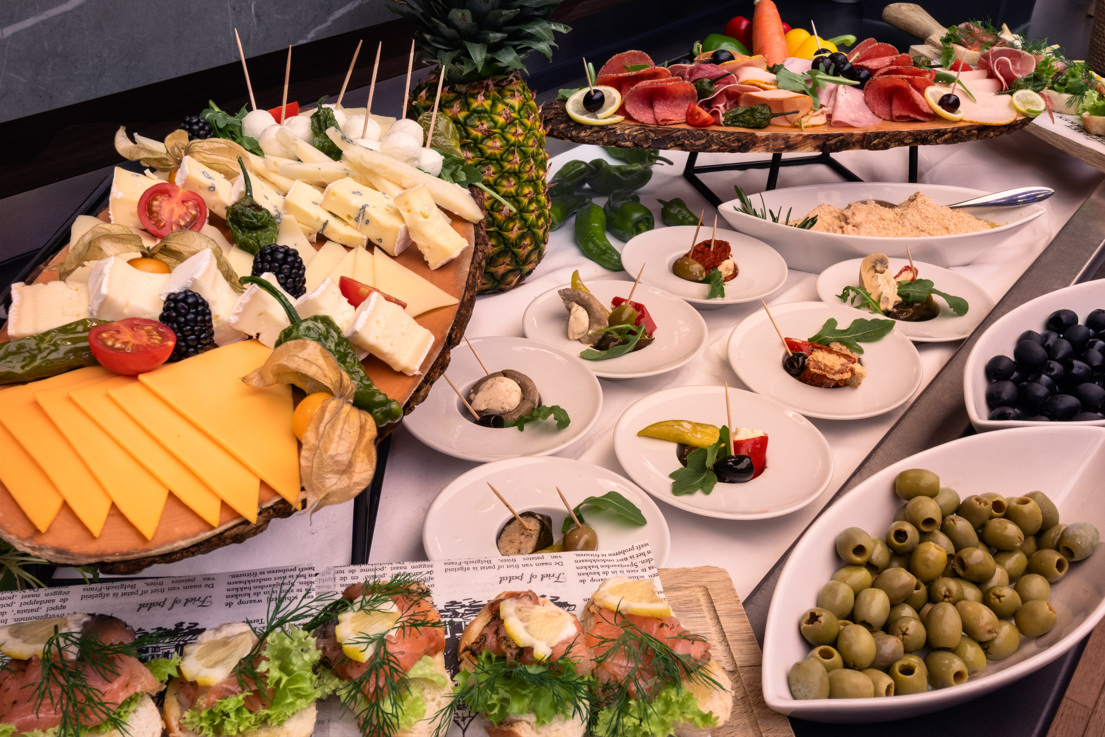 Gourmet buffet with cheese, charcuterie, salmon, olives, and appetizers.