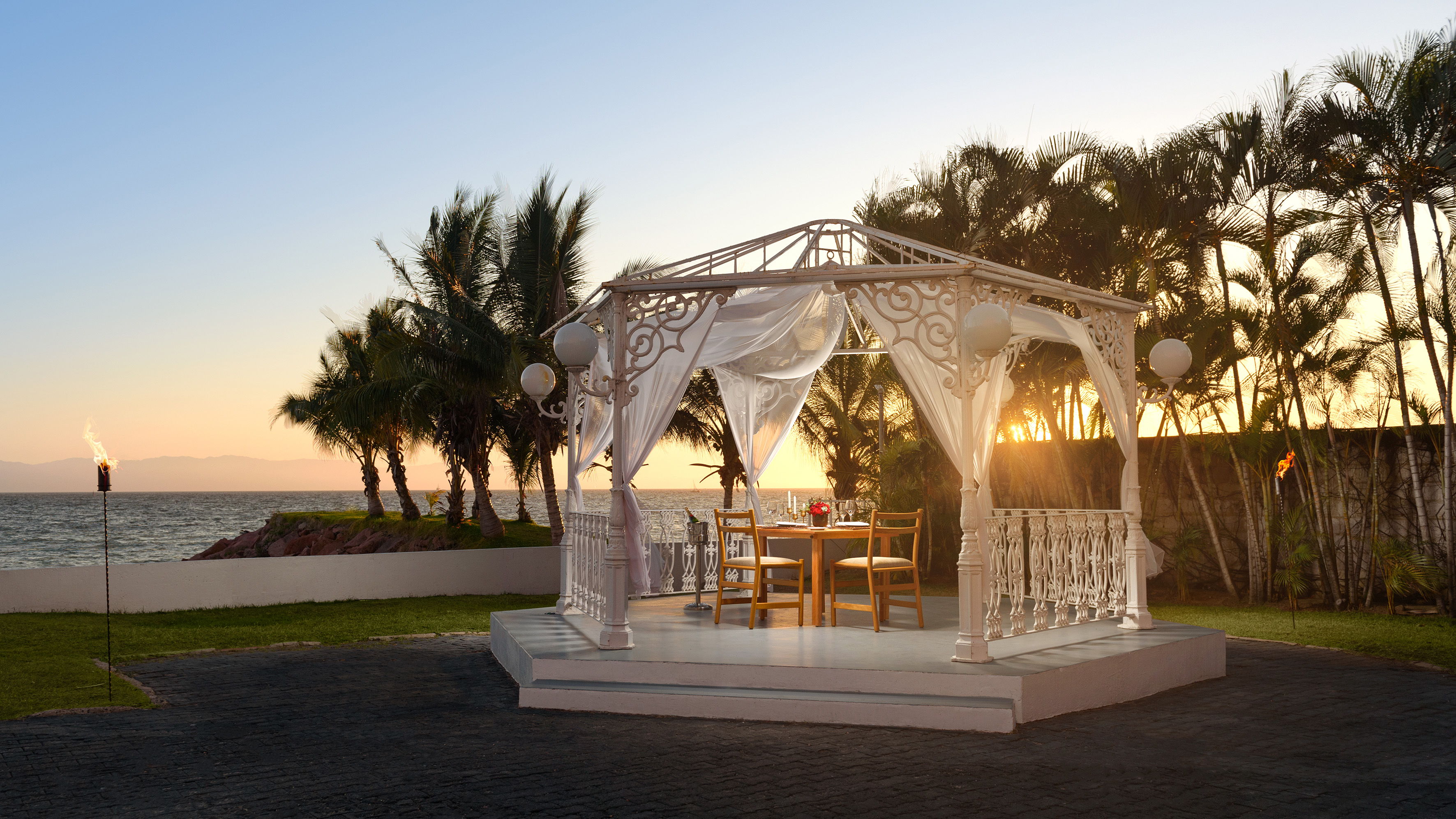 Tropical sunset dinner in romantic white gazebo by ocean.