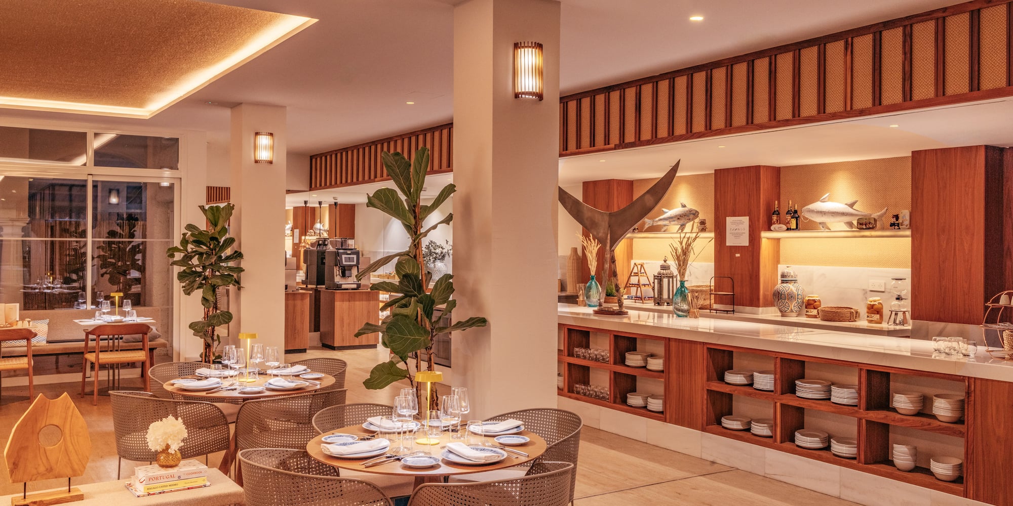 Warm modern restaurant interior with set dining tables and a chic buffet.
