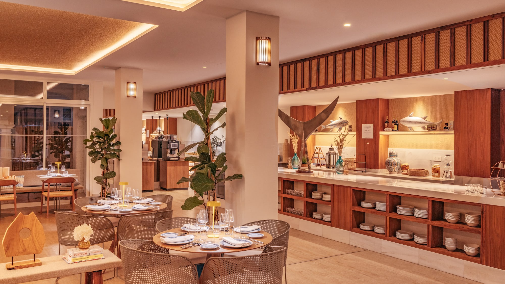 Warm modern restaurant interior with set dining tables and a chic buffet.