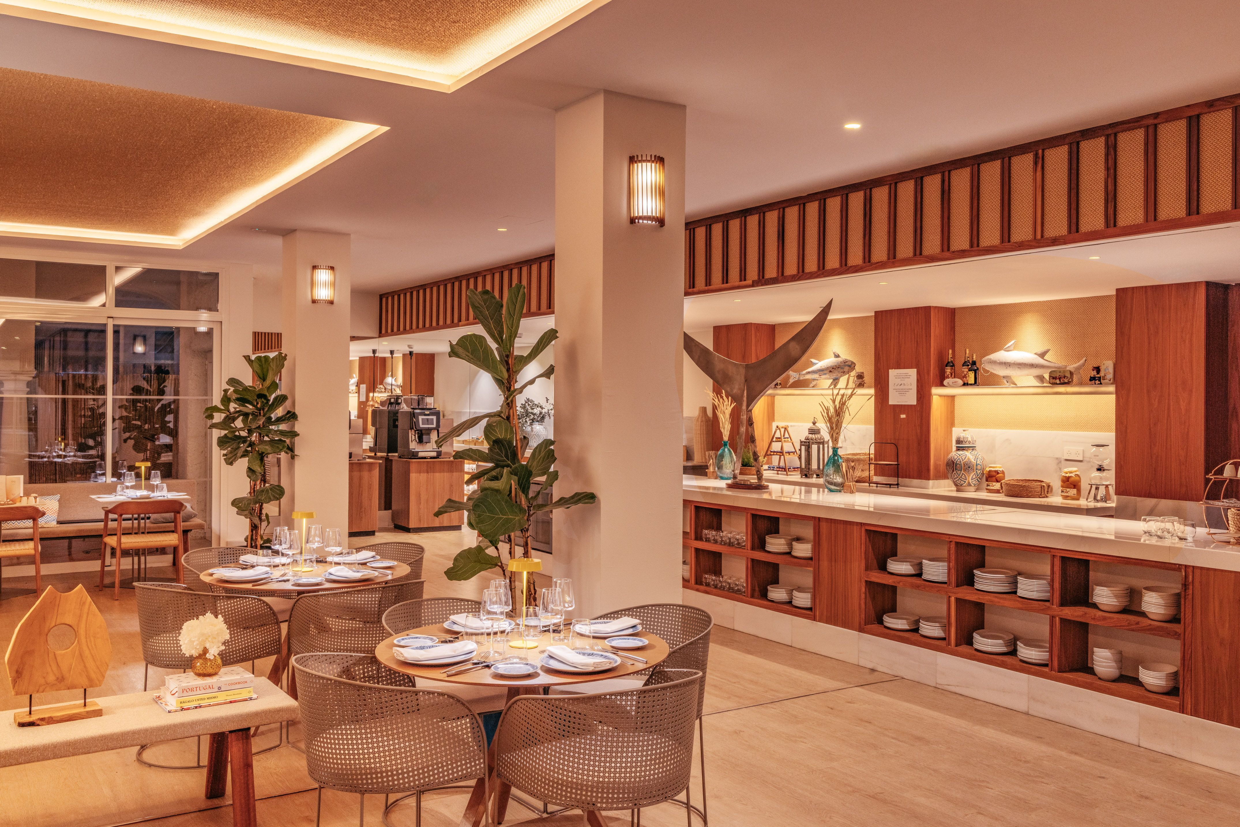 Warm modern restaurant interior with set dining tables and a chic buffet.