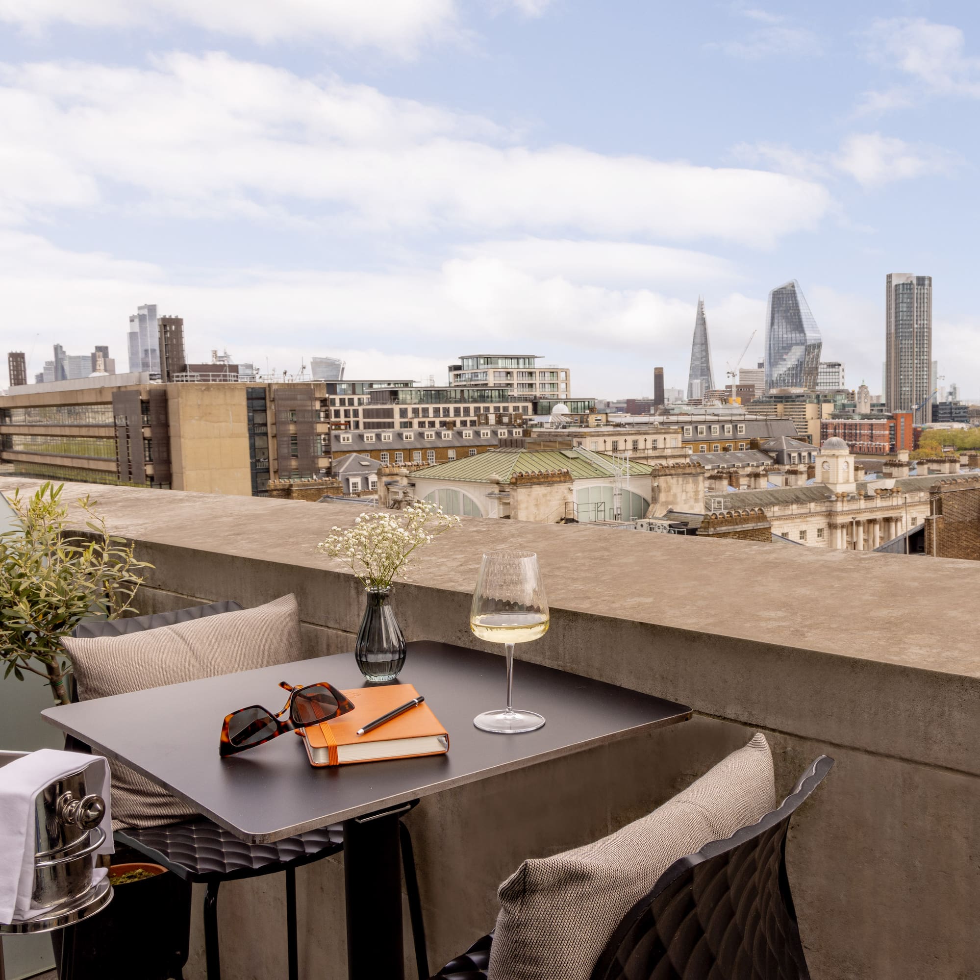 a table with glasses and a book on it with a city in the background