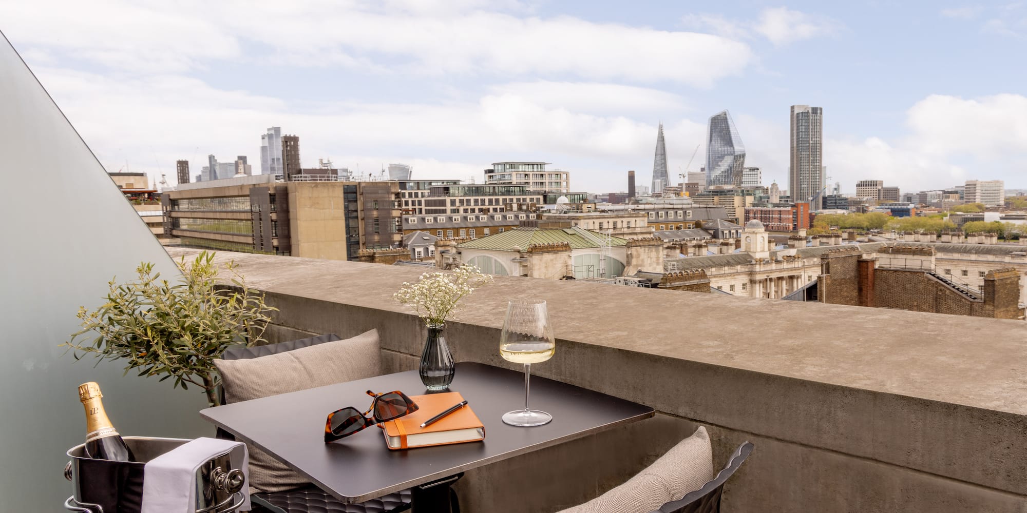 a table with glasses and a book on it with a city in the background