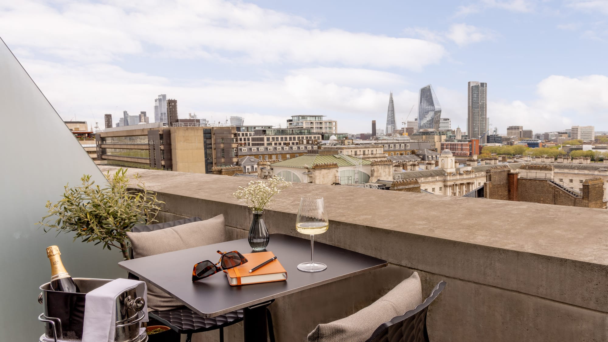 a table with glasses and a book on it with a city in the background
