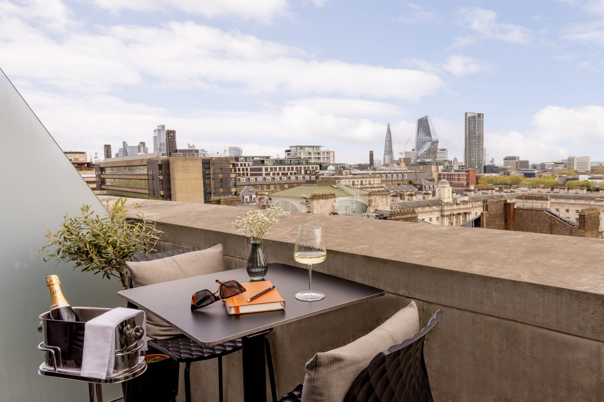 a table with glasses and a book on it with a city in the background
