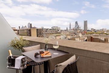 a table with glasses and a book on it with a city in the background