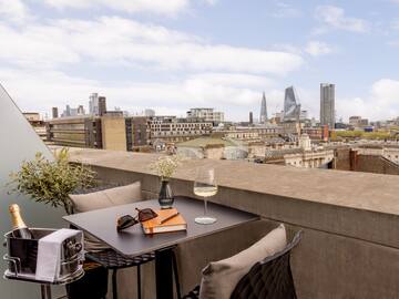 a table with glasses and a book on it with a city in the background