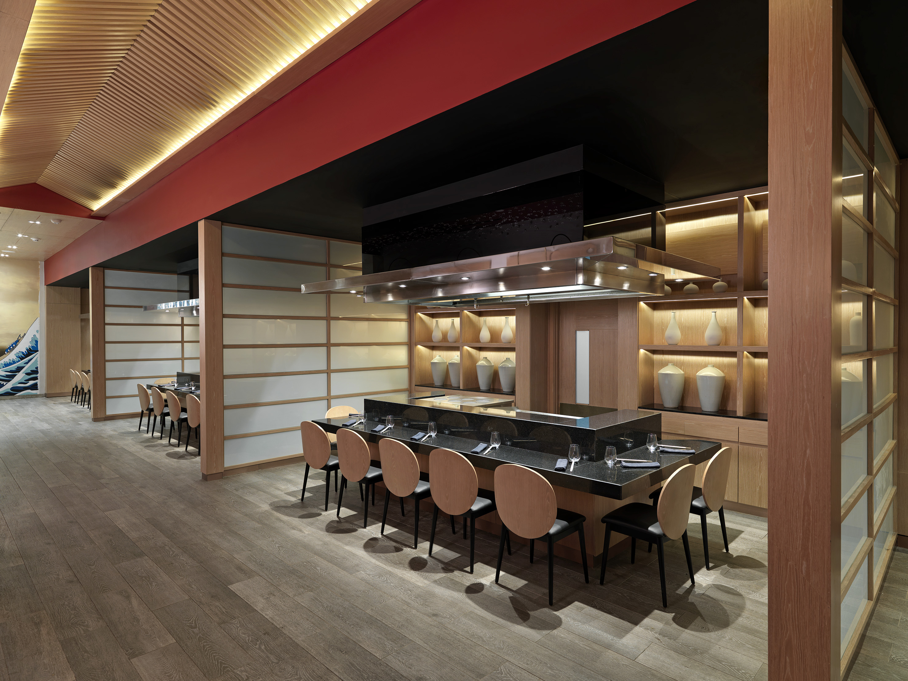 Modern Japanese teppanyaki restaurant interior with wood ceilings and counter seating.