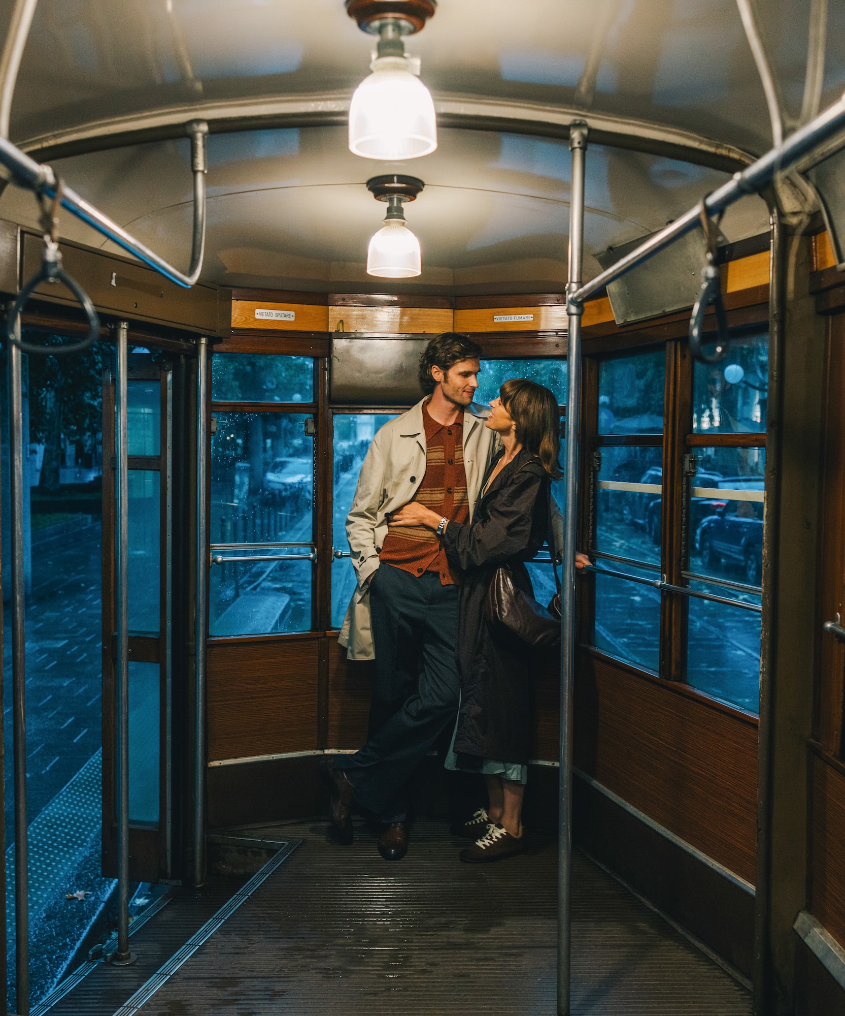 A romantic couple hugging inside a vintage tram during an evening ride.