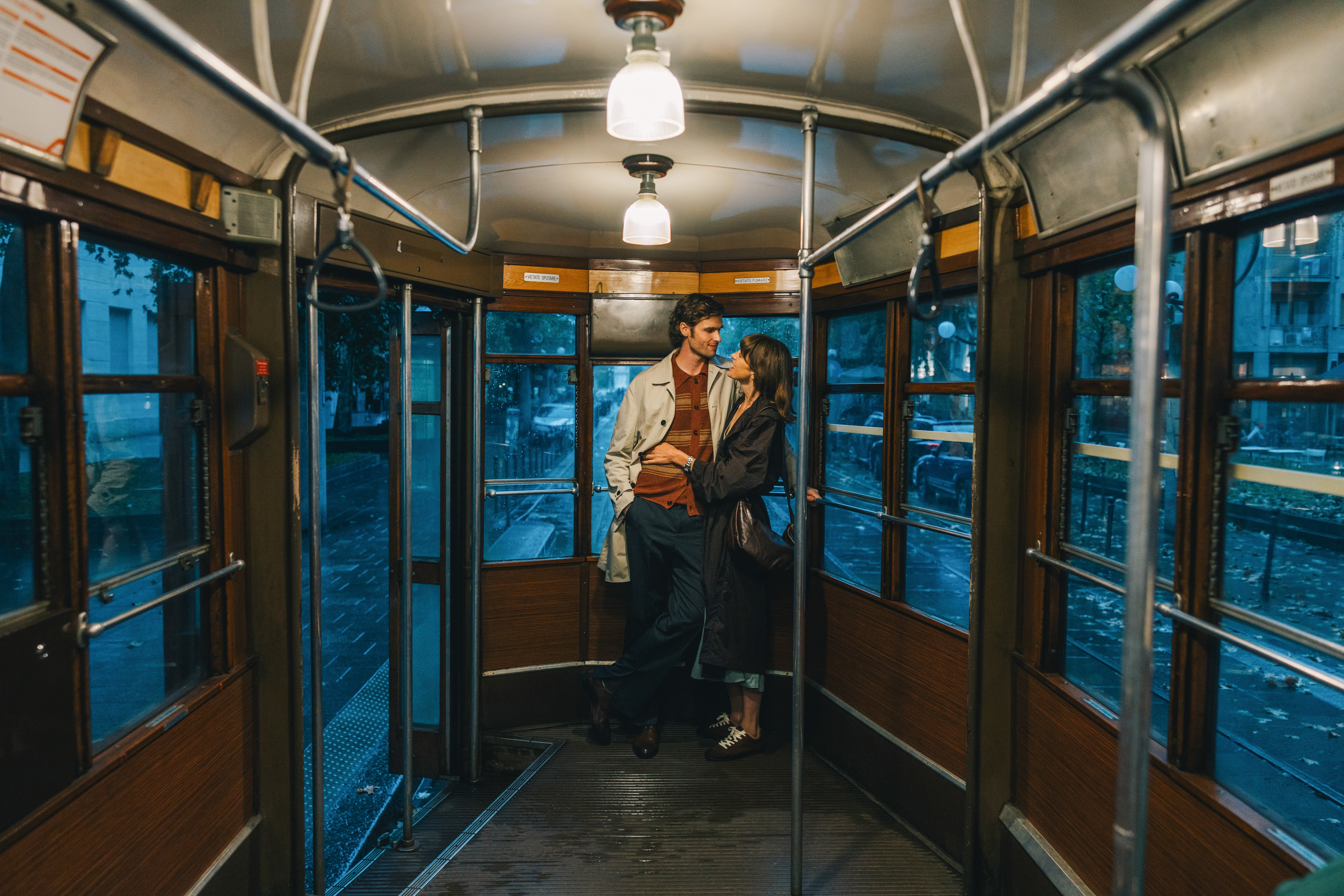 A romantic couple hugging inside a vintage tram during an evening ride.