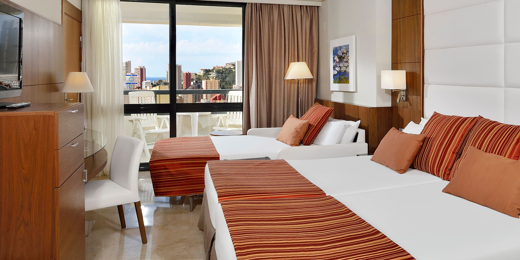 a room with two beds and a table with a window