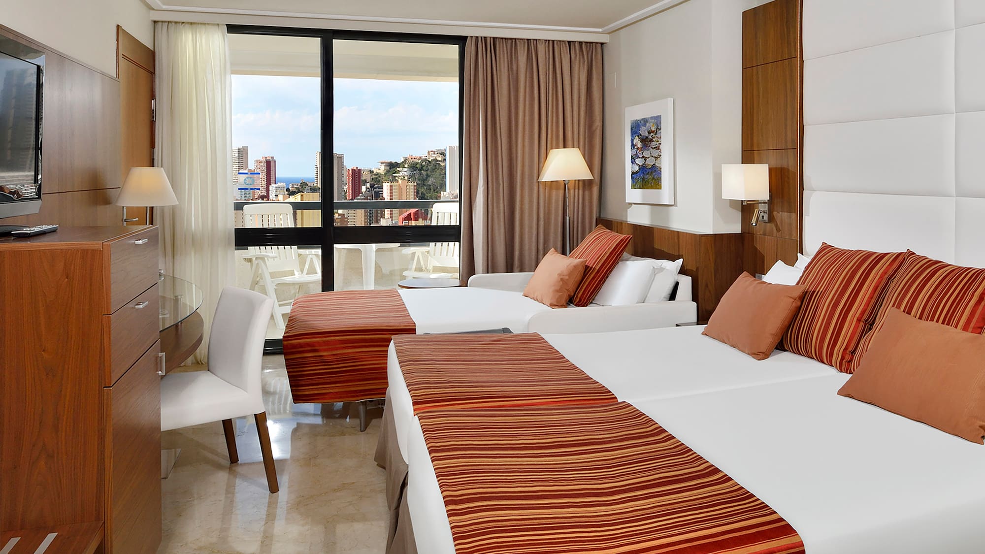 a room with two beds and a table with a window