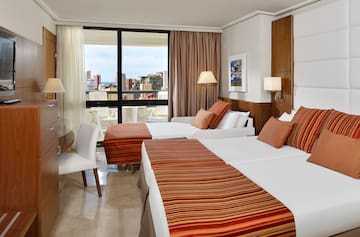 a room with two beds and a table with a window