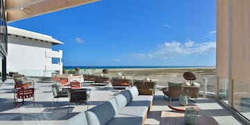 a patio with chairs and tables on a beach