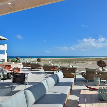 a patio with chairs and tables on a beach
