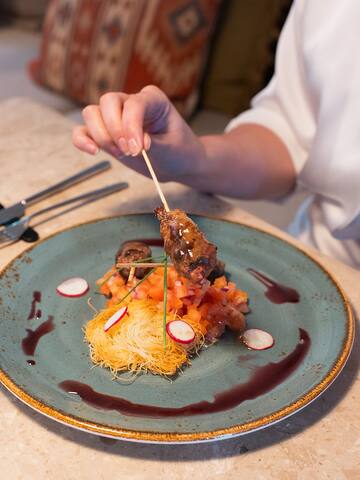 a person holding a skewer of meat on a plate