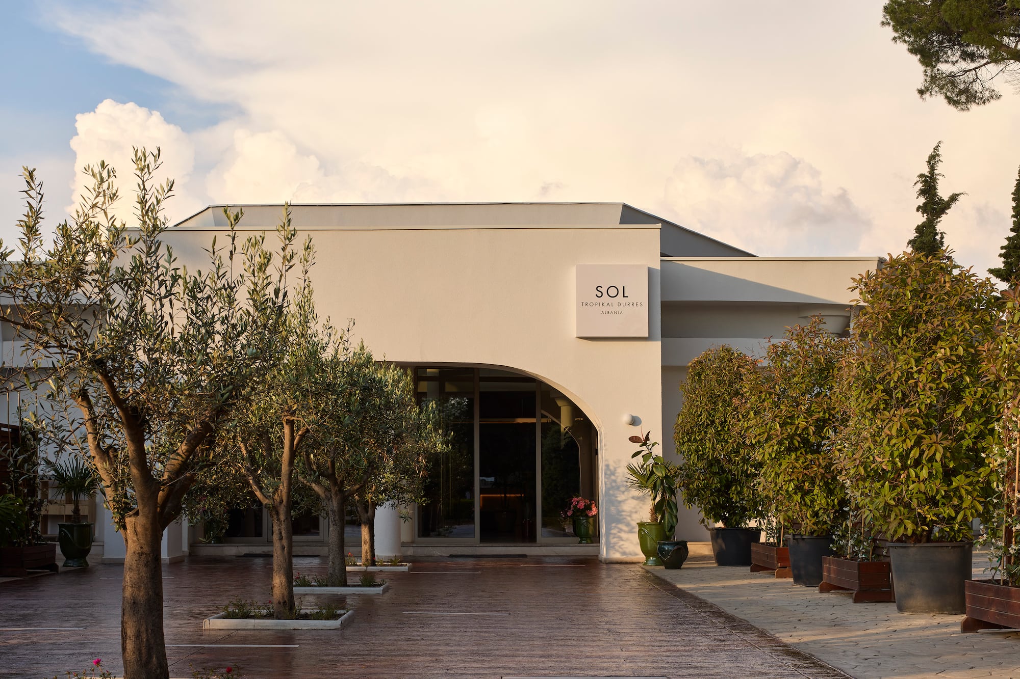 Sol Tropical Durres, Albania hotel entrance with modern building and olive trees.