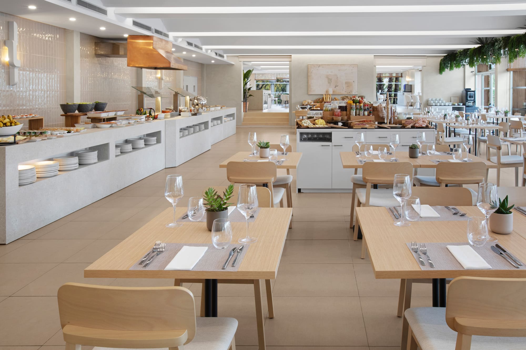 Bright, modern hotel restaurant buffet with clean set tables and food displays.