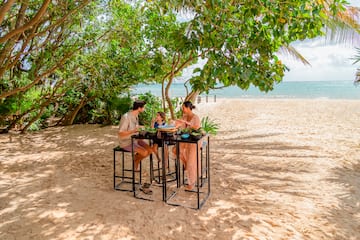 a group of people eating at a table on a beach