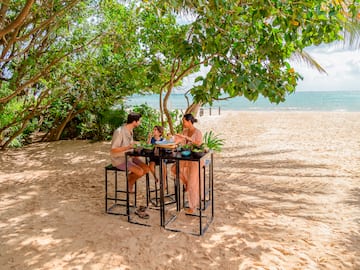 a group of people eating at a table on a beach